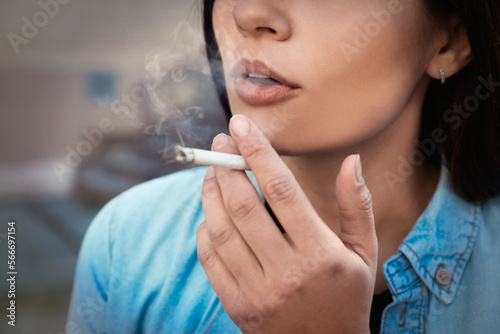 Young woman smoking cigarette outdoors, closeup view