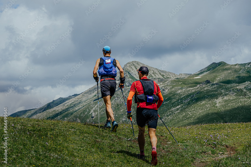 two athletes walk mountain trail during marathon
