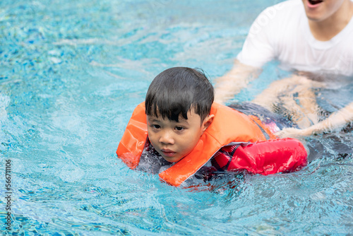Father teaching son to swim at swimming pool. family outdoor activity on holiday in summer weather © winnievinzence