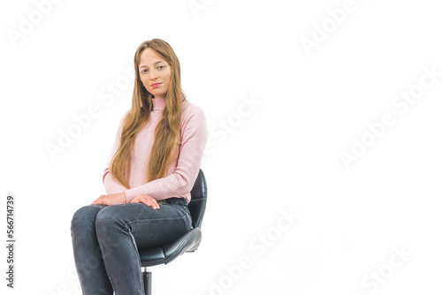 Young long-haired serious woman sitting on a chair in front of white background. High quality photo
