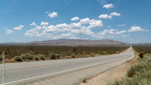 Desert road leading to Tehachapi mountains in the Mojave region with passing clouds and some traffic. . photo