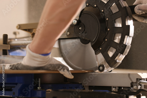 Construction worker sawing wooden board with power end saw closeup