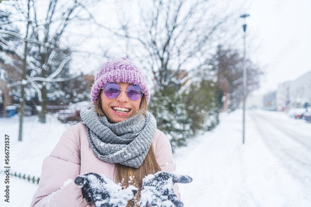 Fototapeta premium Smiling woman showing hands full of snow to the camera outdoor. High quality photo