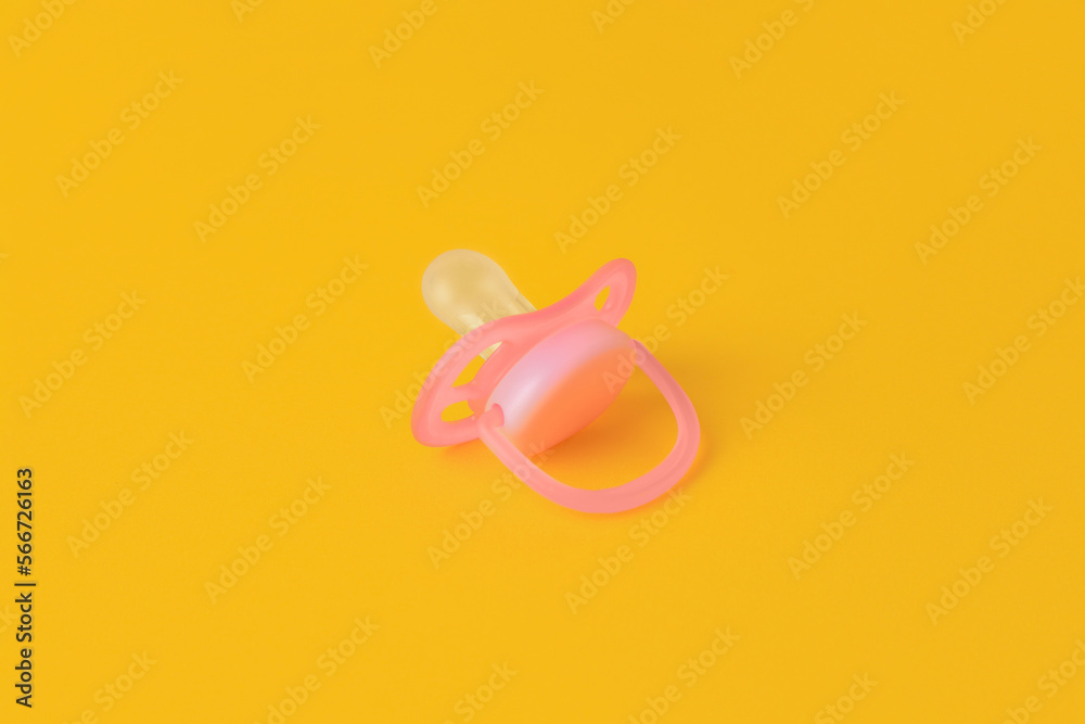 One new baby pacifier on orange background One new baby pacifier on orange background