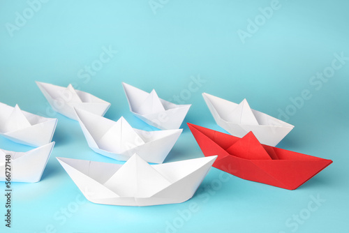 Fototapeta Naklejka Na Ścianę i Meble -  Group of paper boats following red one on light blue background. Leadership concept