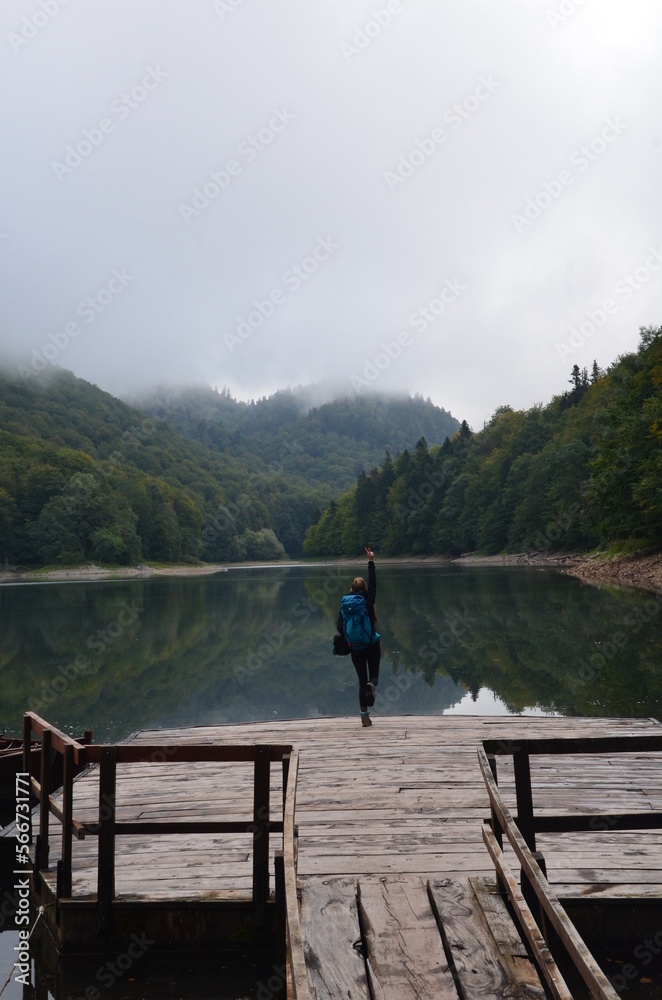 A woman standing on a wooden platform by the Biograd lake during a cloudy morning. Biogradska Gora National Park - Montenegro