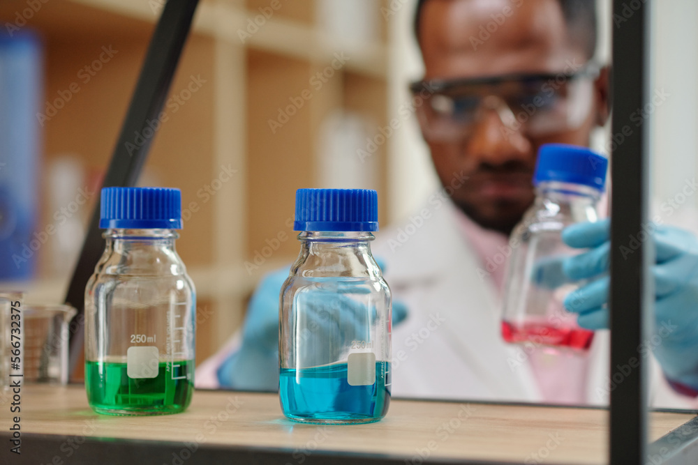 Small bottles with colorful reagents on shelf in laboratory Small bottles with colorful reagents on shelf in laboratory