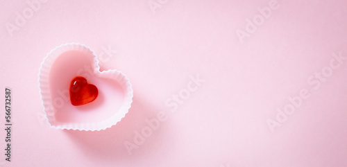 Fototapeta Naklejka Na Ścianę i Meble -  One muffin shape with a red heart on a pink background.