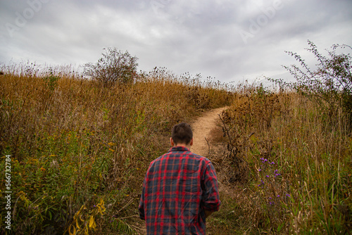 A man walking in a forest and grass field in Canada.