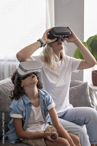 Mother and son wearing virtual reality headset vr glasses in living room at home having fun interacting with virtual reality playing games