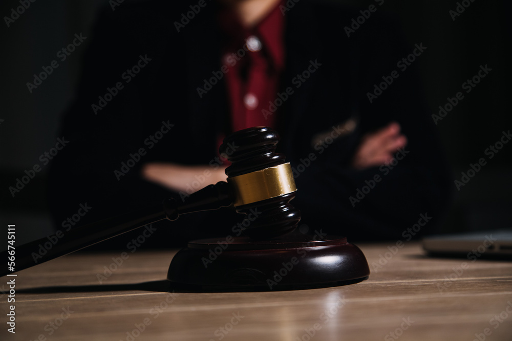 Justice and law concept.Male judge in a courtroom with the gavel, working with, computer and docking keyboard, eyeglasses, on table in morning light