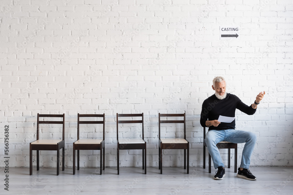 Fototapeta premium bearded middle aged actor reading screenplay while waiting for casting in hall.
