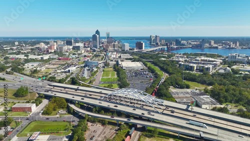 Aerial view of Jacksonville city with high office buildings and american freeway intersection with fast moving cars and trucks. USA transportation infrastructure concept