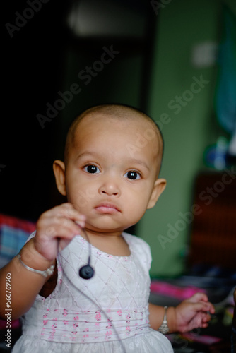 South asian little adorable baby girl smiling on the bed , cute child in home, close up portrait of a toddler 