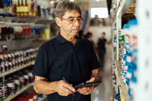 Elderly man working in a hardware store. Small business concept.