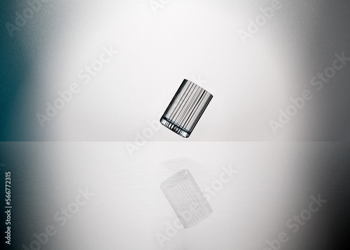 Empty ribbed glass, levitating in mid air against white and blueish studio background.