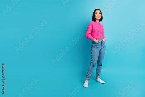 Full size photo of cheerful lovely girl put hands pockets look empty space isolated on blue color background