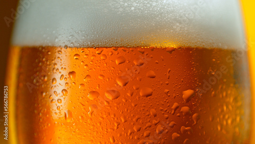 Fotografia Freshly brewed beer in a pint on orange gradient background, close-up