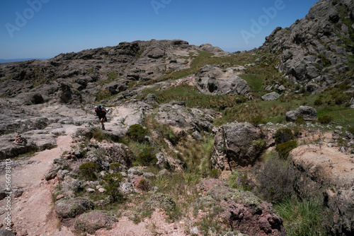 View of a woman hiking along the path in the rock massif Los Gigantes in Cordoba, Argentina. View of the rocky hills in a sunny day. 