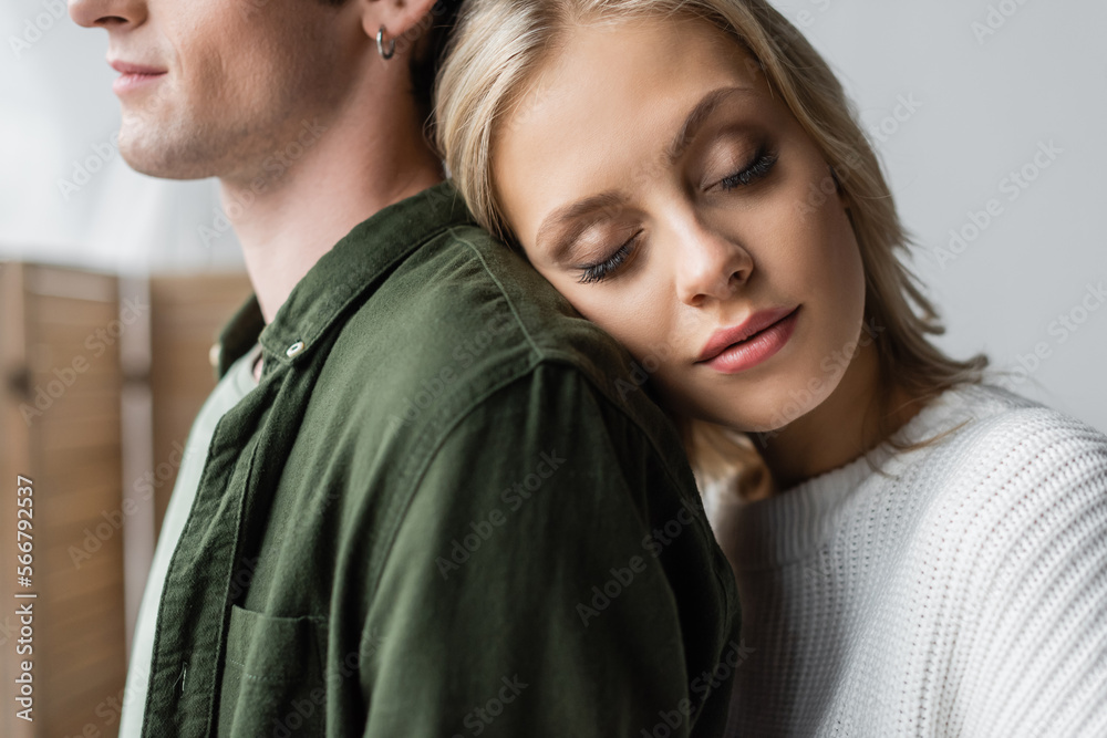portrait of young blonde woman with closed eyes leaning on back of man. portrait of young blonde woman with closed eyes leaning on back of man.