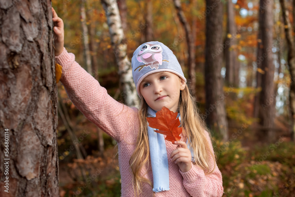 girl with red leaf in autumn forest