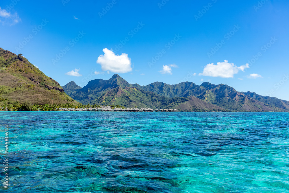 lagon bleu turquoise sur fond des montagnes er bungalow sur pilotis à Moorea en Polynésie 