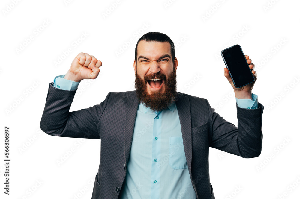 Young overjoyed bearded man shouts as a winner while holding his phone. Young overjoyed bearded man shouts as a winner while holding his phone.