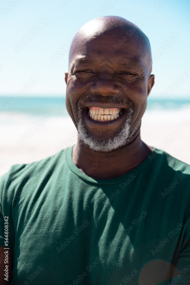 Close-up portrait of cheerful bald african american senior man smiling at beach against clear sky Close-up portrait of cheerful bald african american senior man smiling at beach against clear sky