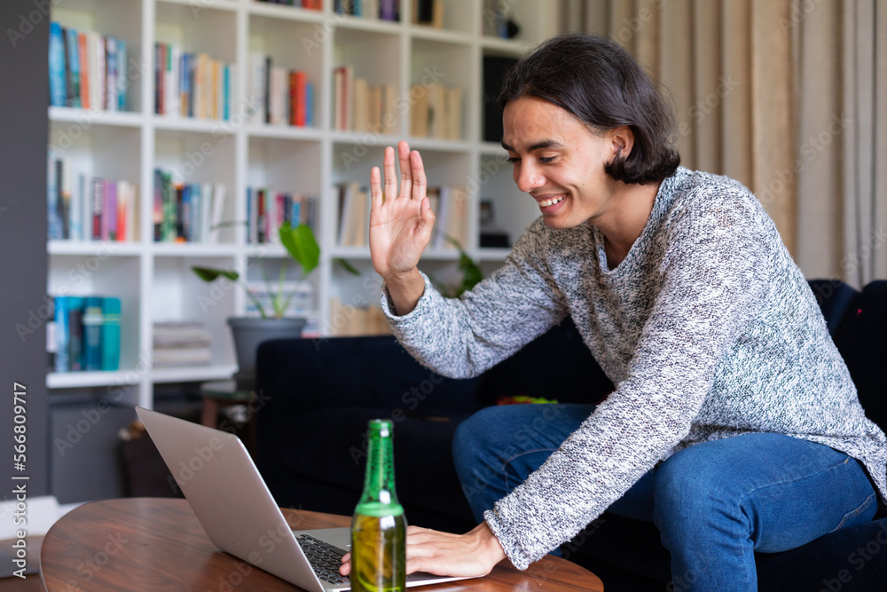 Happy biracial man sitting on sofa, using laptop for video call Happy biracial man sitting on sofa, using laptop for video call