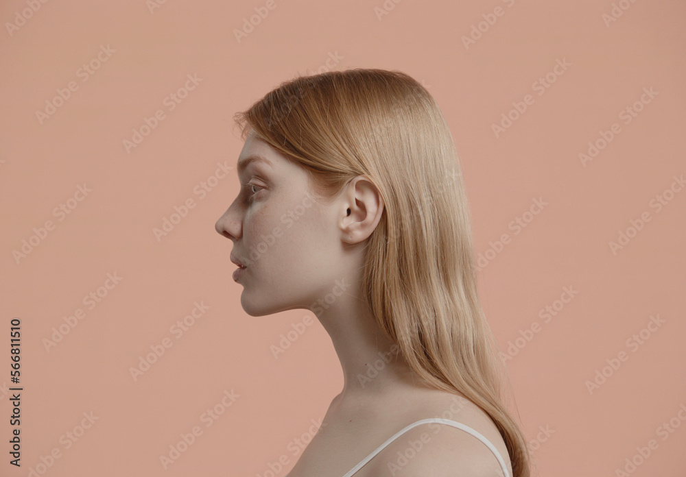 Portrait of beautiful 20s fashion model Caucasian female with no make-up posing, looking into camera against light brown pastel colored background Portrait of beautiful 20s fashion model Caucasian female with no make-up posing, looking into camera against light brown pastel colored background