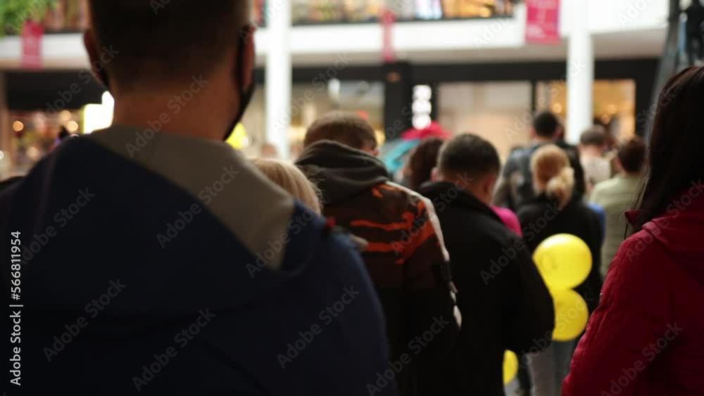 Queue of people, crowd waiting, line inside. Group of people are standing in queue indoors in shopping mall, waiting for something to happen.