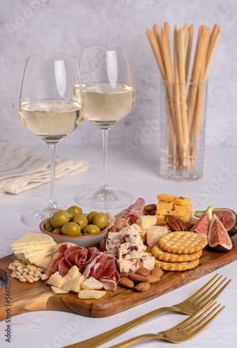 Food photography of white wine, salami, grissini, cracker, cheese, fig, parmesan, prosciutto, cheddar, olive, almond, nuts