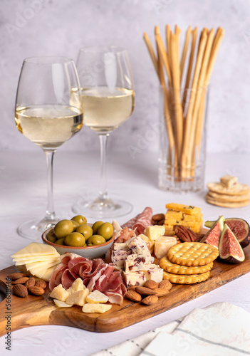 Food photography of white wine, salami, grissini, cracker, cheese, fig, parmesan, prosciutto, cheddar, olive, almond, nuts