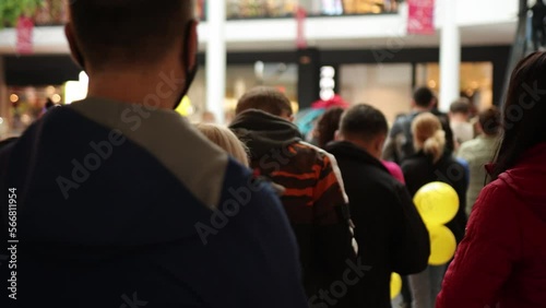Queue of people, crowd waiting, line inside. Group of people are standing in queue indoors in shopping mall, waiting for something to happen.