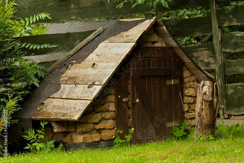 Komórka , szopa , mała chatka gospodarcza zbudowana z kamieni i drewna w pobliżu płotu na podwórku . 