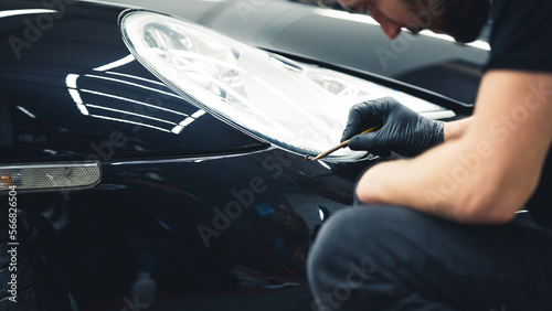 Bild auf Leinwand Gentle black car paint touch-ups done with a small brush in the area of headlights