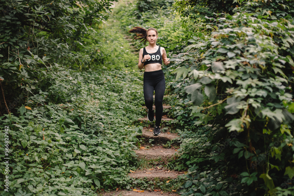 Front view of young woman running down stairs in park Front view of young woman running down stairs in park