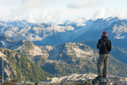 A hiker looks out a a beautfiul mountain view from a rocky ridge. photo