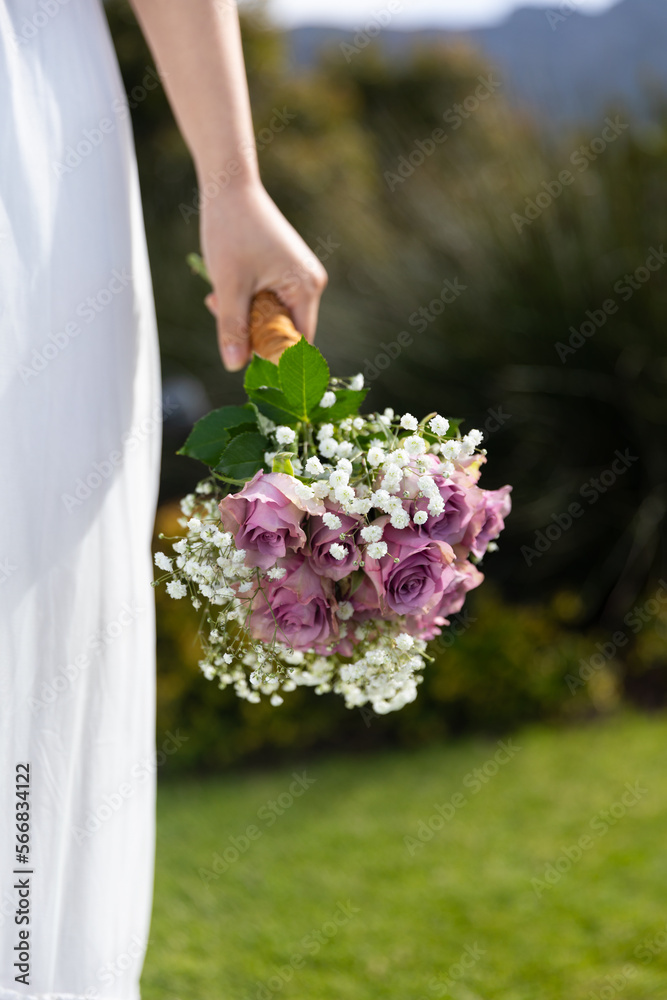 Vertical midsection of bride holding bouquet at outdoor wedding, copy space Vertical midsection of bride holding bouquet at outdoor wedding, copy space