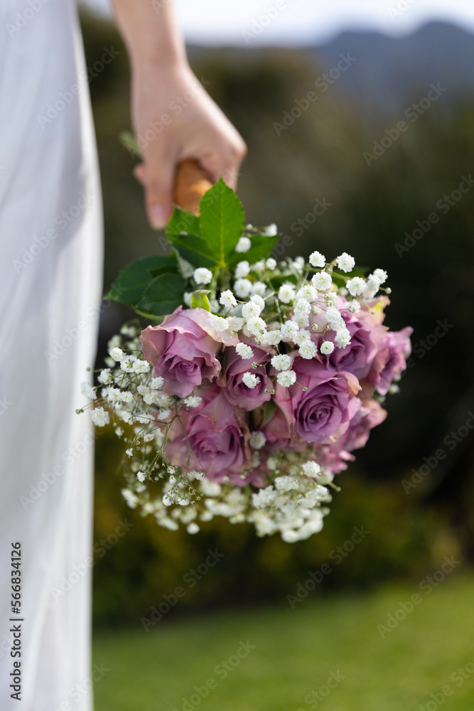 Vertical midsection of bride holding bouquet at outdoor wedding, copy space Vertical midsection of bride holding bouquet at outdoor wedding, copy space