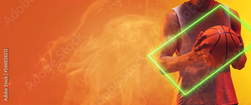Midsection of biracial muscular basketball player holding ball by rectangle on orange background