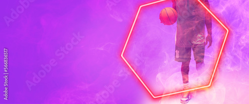 Low section of african american basketball player with ball walking by hexagon on purple background