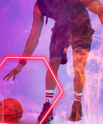 Low section of biracial basketball player dribbling ball by glowing hexagon on violet background