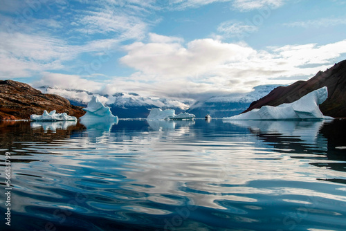 Floating icebergs with snowy mountains and a ship in the background