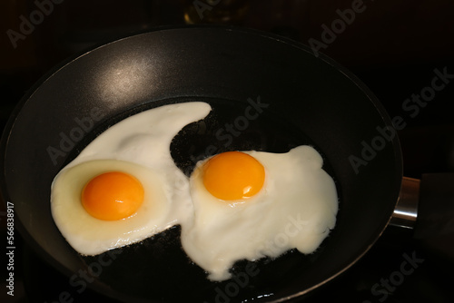 Cooking eggs for breakfast in frying pan on cooktop