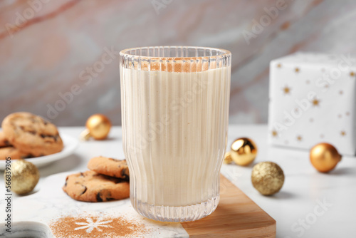 Glass of delicious eggnog with cinnamon on white table