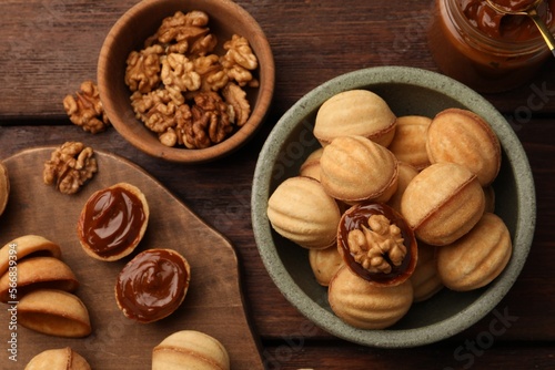 Delicious nut shaped cookies with boiled condensed milk on wooden table  flat lay