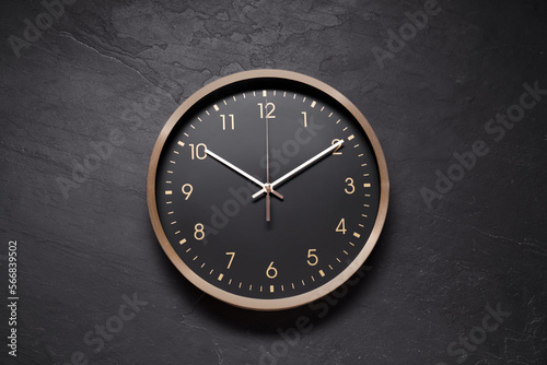 Stylish round clock on black table, top view. Interior element