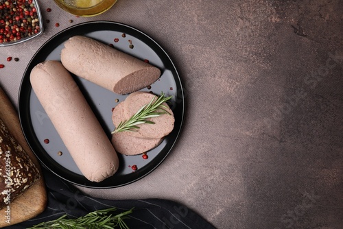 Delicious liver sausages with rosemary on brown textured table  flat lay. Space for text