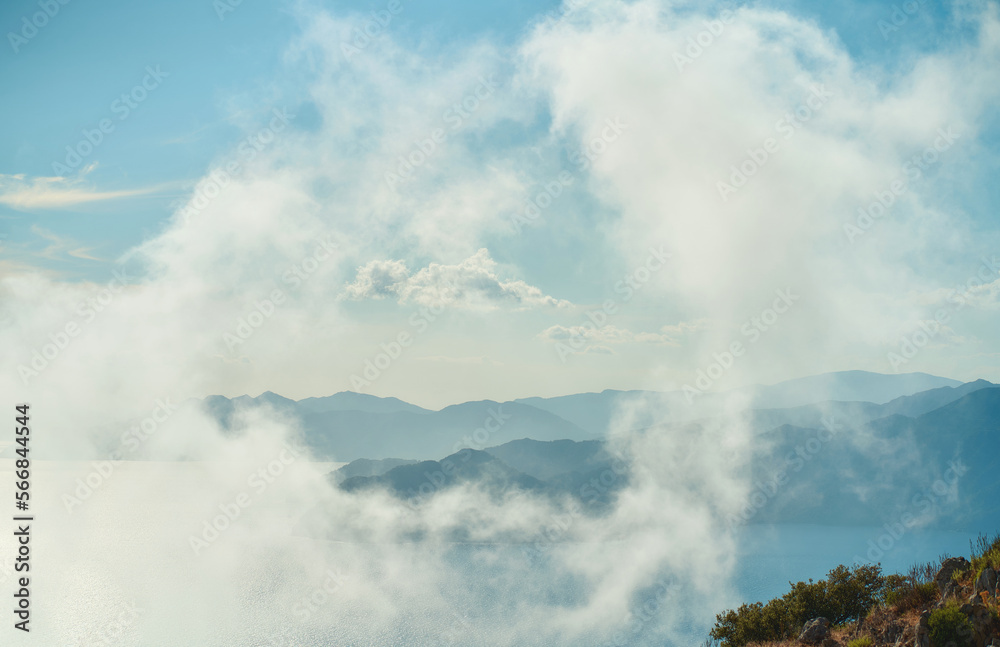 Obraz premium Scenic landscape of mountains in clouds and rocky steep coast of the Aegean Sea in Turkey.
